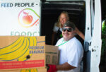 A man is unloading produce boxes off a food pantry van.